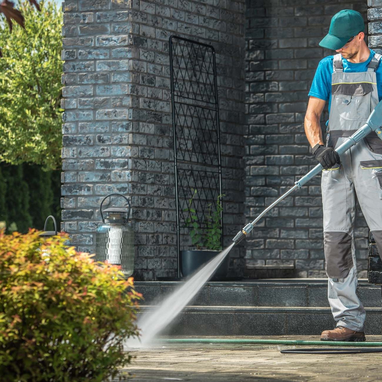 Driveway Pressure Washing. Caucasian Worker Cleaning Area in Front of the House