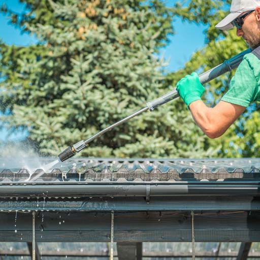 Roof and Gutters Cleaning. Roof and Gutters Power Cleaning Using Pressure Washer. Caucasian Worker.